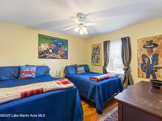 bedroom with a textured ceiling, ceiling fan, and wood finished floors