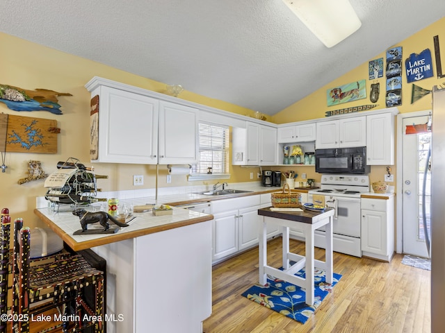 kitchen with white range with electric cooktop, tile countertops, a peninsula, white cabinets, and black microwave