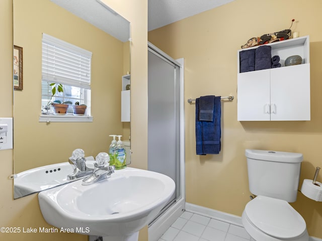 bathroom featuring a sink, baseboards, a stall shower, and tile patterned floors