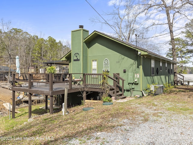 exterior space featuring a wooden deck, cooling unit, and a chimney