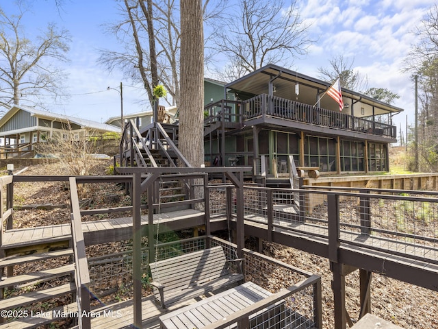 back of property featuring a deck, stairs, and a sunroom