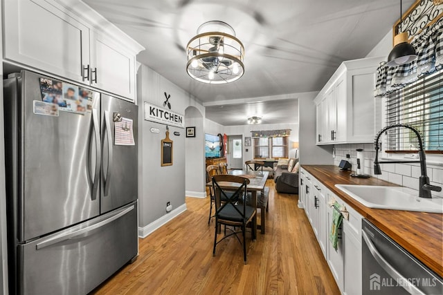 kitchen featuring stainless steel appliances, wood counters, a sink, and plenty of natural light