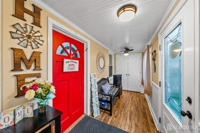 foyer entrance featuring wood finished floors, crown molding, and ceiling fan