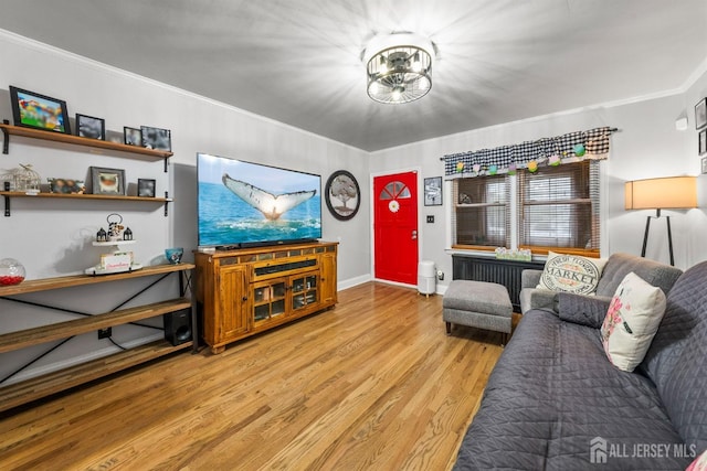 living room with light wood-style flooring, crown molding, and baseboards