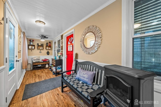 foyer featuring wood finished floors, ornamental molding, wainscoting, and a ceiling fan