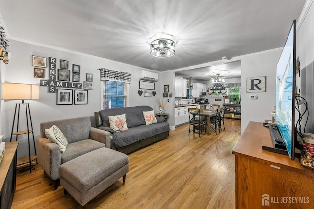 living area with a chandelier, light wood finished floors, a wall mounted AC, and crown molding