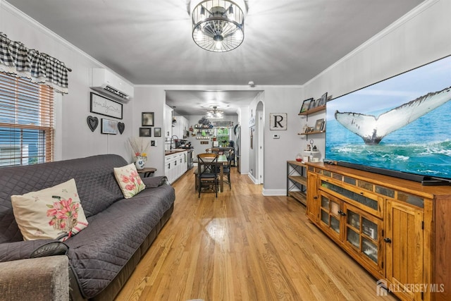 living area featuring an AC wall unit, light wood-style flooring, plenty of natural light, crown molding, and arched walkways