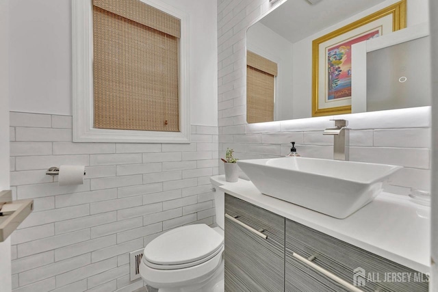 bathroom featuring tile walls, vanity, and toilet