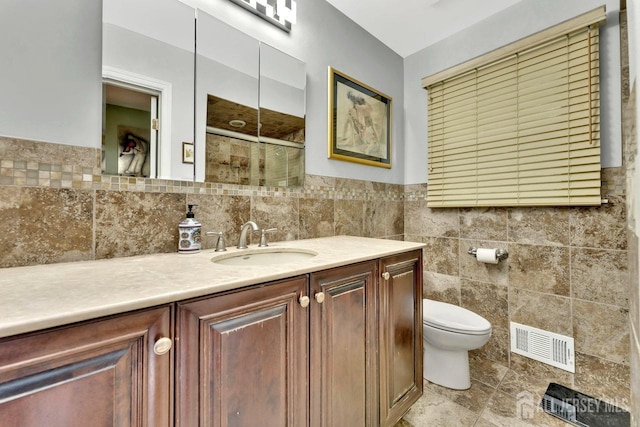 bathroom with toilet, tile walls, vanity, and walk in shower