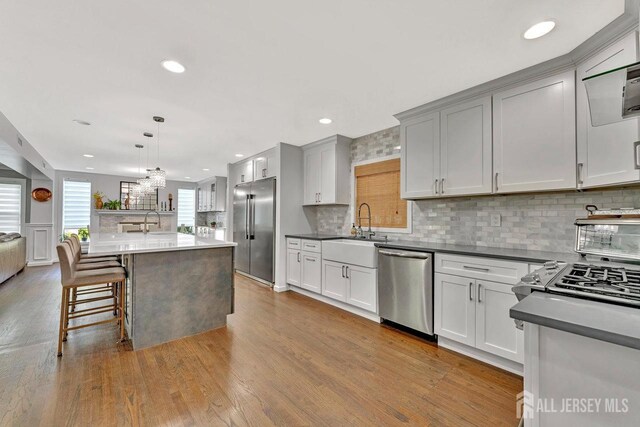 kitchen with sink, appliances with stainless steel finishes, a center island, decorative backsplash, and decorative light fixtures