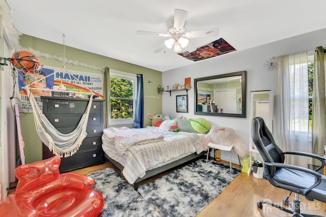 bedroom with hardwood / wood-style flooring, ceiling fan, and multiple windows