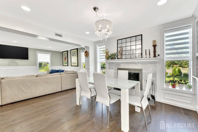 dining area featuring hardwood / wood-style flooring, a brick fireplace, and a chandelier