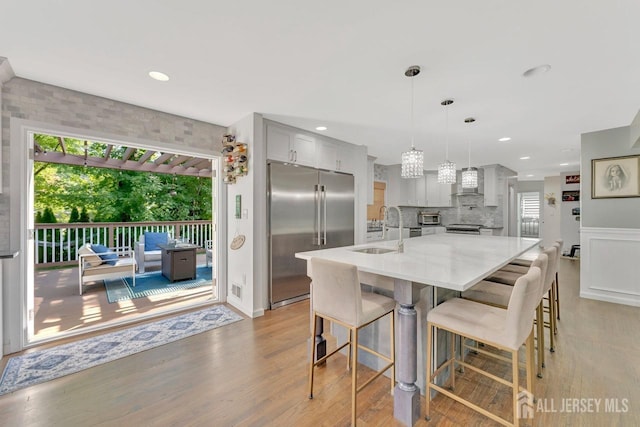 kitchen featuring sink, hanging light fixtures, gray cabinets, stainless steel appliances, and wall chimney range hood