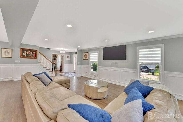 living room with crown molding, a healthy amount of sunlight, and light wood-type flooring