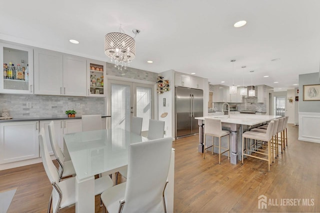 dining room featuring a notable chandelier, sink, light hardwood / wood-style flooring, and french doors