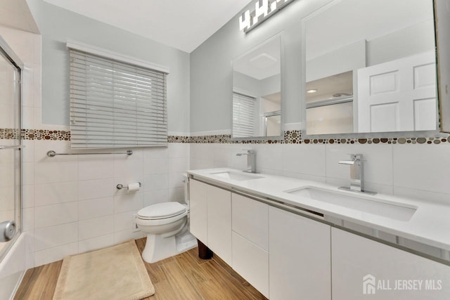 bathroom with hardwood / wood-style flooring, vanity, toilet, and tile walls