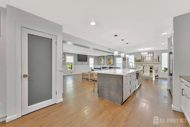 kitchen featuring decorative light fixtures, white cabinetry, sink, a breakfast bar area, and a large island with sink