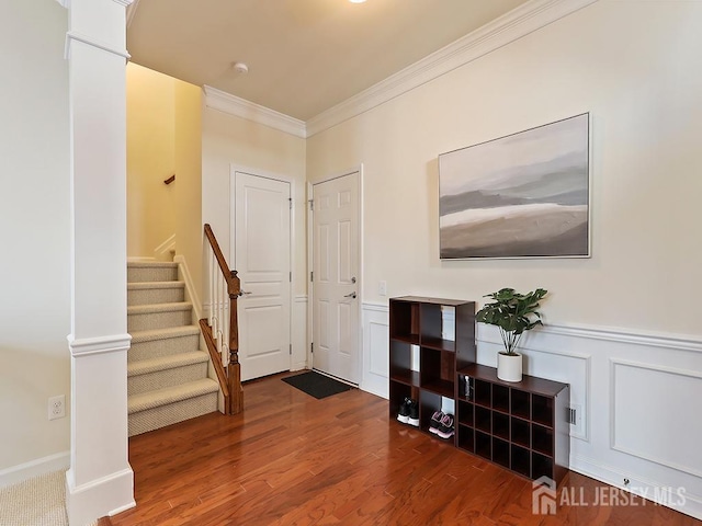 entrance foyer with wood finished floors, ornate columns, stairs, wainscoting, and crown molding