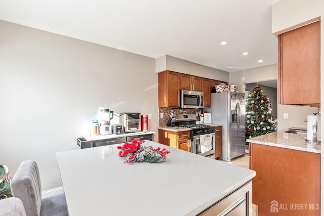 kitchen featuring appliances with stainless steel finishes, light stone counters, and decorative backsplash