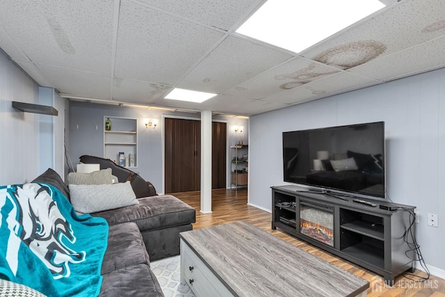 living room with light hardwood / wood-style floors and a drop ceiling