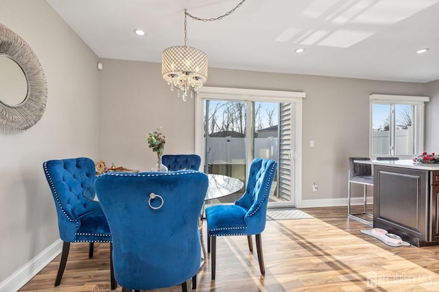 dining area with light wood-type flooring, a wealth of natural light, and an inviting chandelier