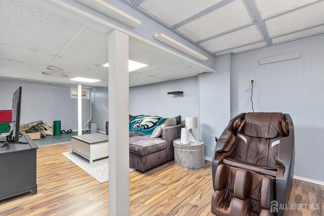 interior space featuring light wood-type flooring, a paneled ceiling, and baseboards