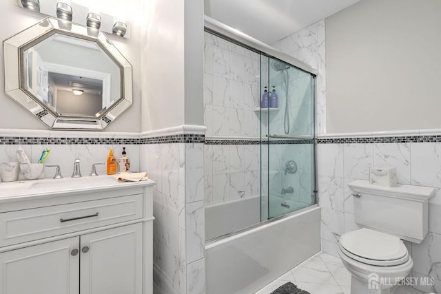 full bathroom featuring vanity, combined bath / shower with glass door, and toilet