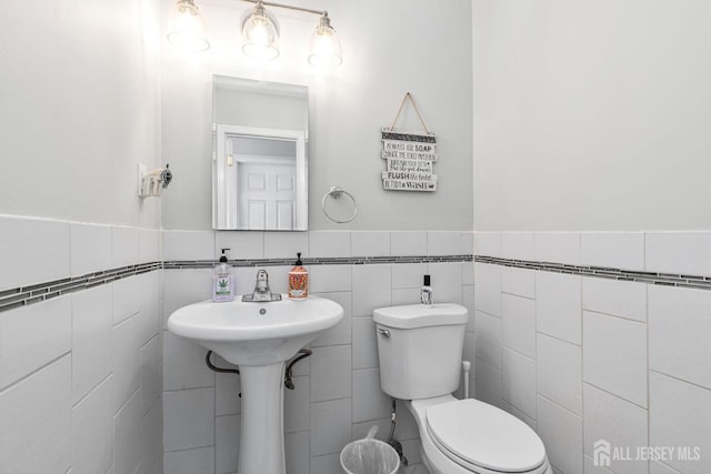 bathroom with tile walls and toilet