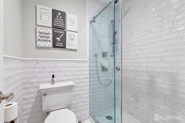 bathroom featuring tile walls, an enclosed shower, and toilet