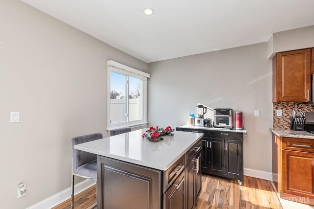 kitchen featuring tasteful backsplash, a kitchen island, a breakfast bar, and light hardwood / wood-style flooring