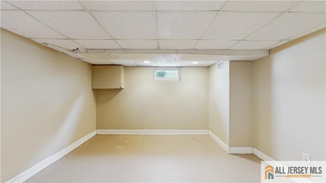 basement with a paneled ceiling, visible vents, and baseboards