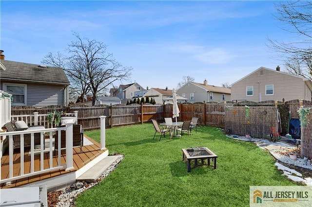 view of yard with a fire pit, a deck, and a fenced backyard