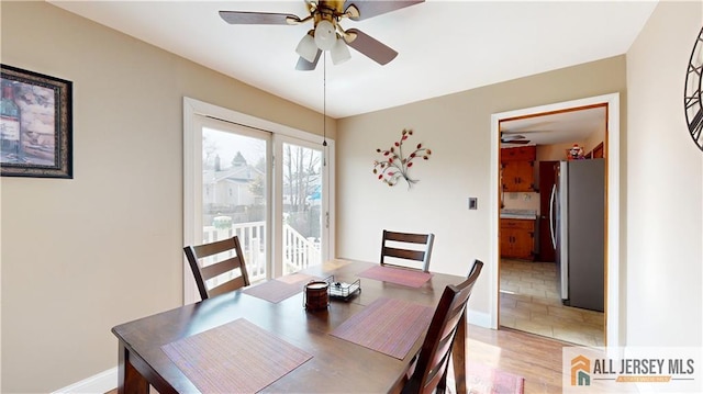 dining area with light wood-style floors, ceiling fan, and baseboards