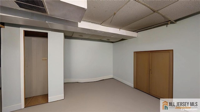 below grade area featuring a drop ceiling, visible vents, and baseboards