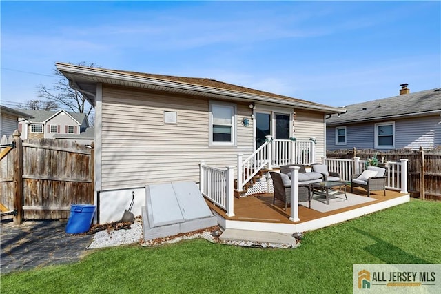 rear view of house featuring fence, a deck, and a lawn