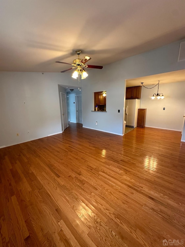 unfurnished living room featuring hardwood / wood-style flooring and ceiling fan with notable chandelier