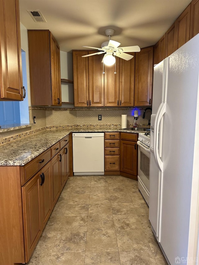 kitchen featuring tasteful backsplash, ceiling fan, light stone countertops, and white appliances