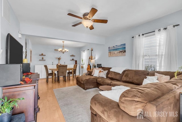 living room featuring ceiling fan with notable chandelier and light wood-type flooring