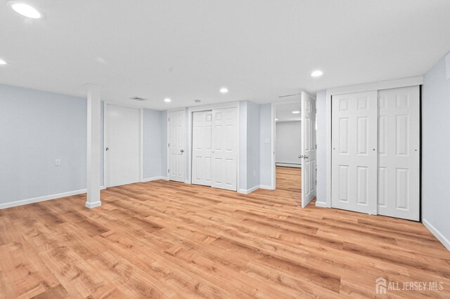finished below grade area with a baseboard radiator, recessed lighting, and light wood-style flooring