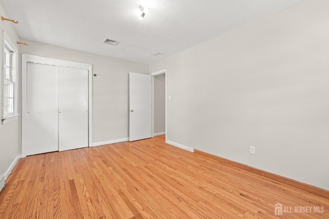 unfurnished bedroom featuring baseboards, visible vents, light wood-style flooring, and a closet