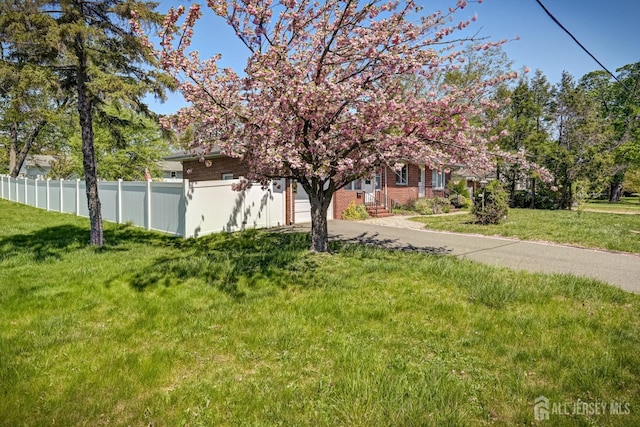 view of yard featuring an attached garage, fence, and driveway
