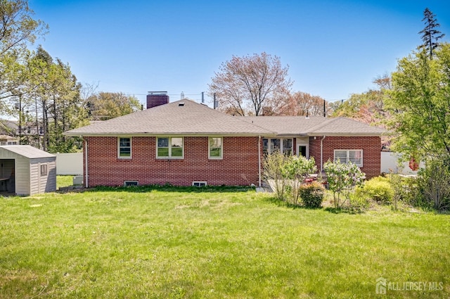 rear view of house featuring a yard, brick siding, an outbuilding, and a chimney