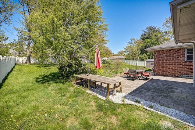 view of yard with a patio, a fenced backyard, a storage shed, and outdoor dining space