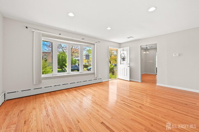 unfurnished living room featuring light wood-style floors, recessed lighting, baseboards, a baseboard radiator, and visible vents