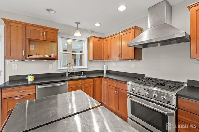 kitchen featuring wall chimney range hood, decorative light fixtures, appliances with stainless steel finishes, brown cabinets, and a sink