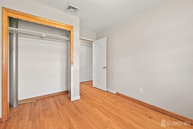 unfurnished bedroom with visible vents, baseboards, a closet, and light wood-type flooring