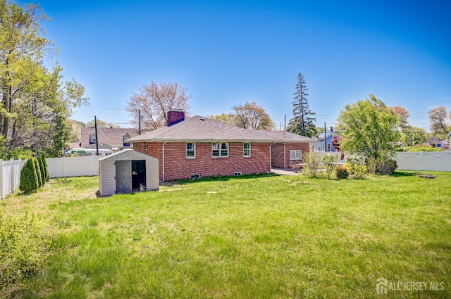 rear view of property featuring a storage unit, a fenced backyard, an outbuilding, and a chimney
