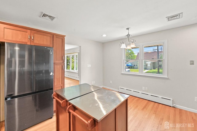 kitchen with freestanding refrigerator, visible vents, a kitchen island, and a baseboard radiator