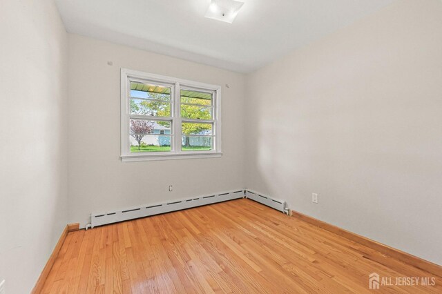 unfurnished room featuring baseboard heating and light wood-style flooring