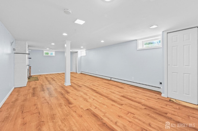 below grade area featuring baseboards, light wood-style flooring, and a baseboard radiator